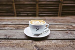 Cofeina – cat de mult, e prea mult. O ceașcă albă de ceramică cu o pictură latte art în formă de inimioară pe suprafața laptelui spumat.