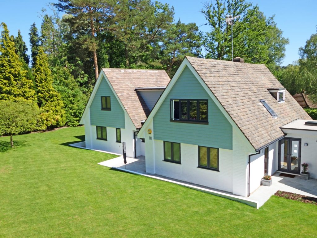 O casă albă cu un acoperiș maro situată pe un teren cu iarbă verde. 