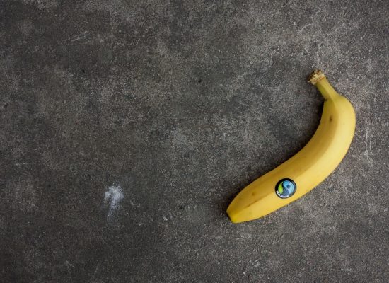 Ce înseamnă marca Fairtrade. Imagine a unei banane galbene pe un fundal gri si simbolul Fairtrade