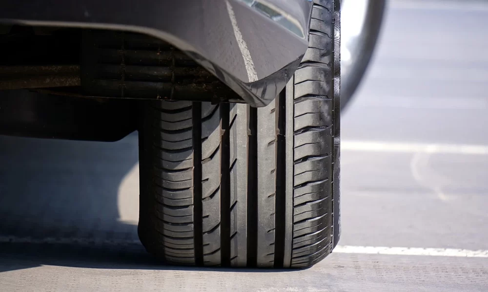 Anvelopă auto cu profil adânc, montată pe o mașină neagră.