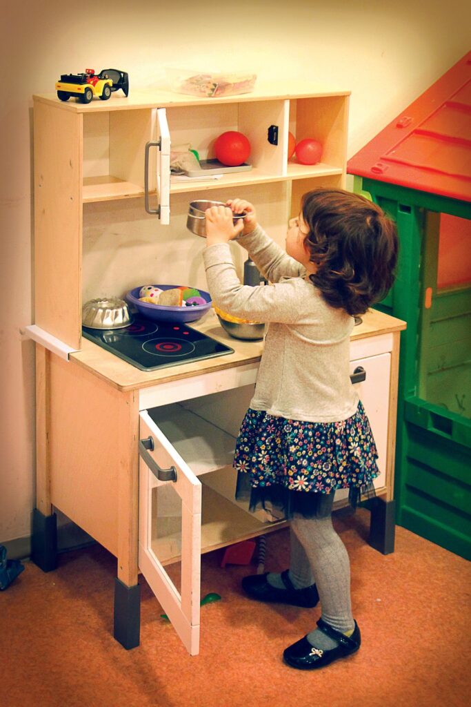 Joc de tip pretend play pentru copii, in care o fetita se joaca cu ustensile de bucatarie