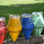Cosuri colorate de reciclare pentru sticla, plastic, hartie si metal amplasate in aer liber, simbol al unui stil de viata sustenabil si al colectarii selective a deseurilor.