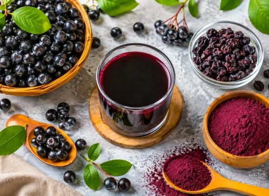 Aronia: beneficii, proprietăți, contraindicații și mod de consum Flat lay cu fructe proaspete de aronia, suc de aronia, fructe uscate și pudră de aronia, prezentând principalele forme de consum.
